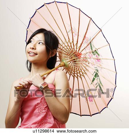 Picture - Close-up of a young woman holding a parasol and looking away. Fotosearch