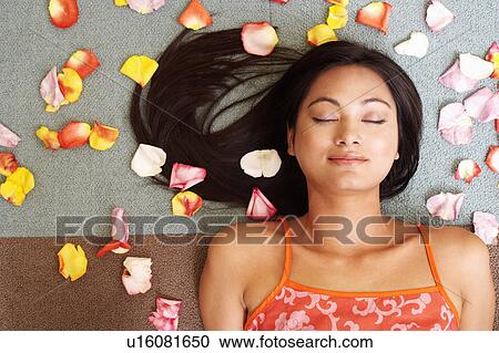 High angle view of a young woman lying down with petals around her View Large Photo Image Stock Image - High angle view of a young woman lying down with petals around her. Fotosearch
