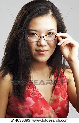 Portrait of a young woman adjusting her eyeglasses View Large Photo Image Stock Image - Portrait of a young woman adjusting her eyeglasses. Fotosearch