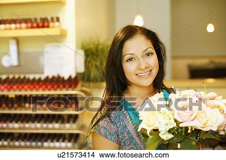 Picture - Portrait of a young woman holding a bunch of flowers and smiling. Fotosearch