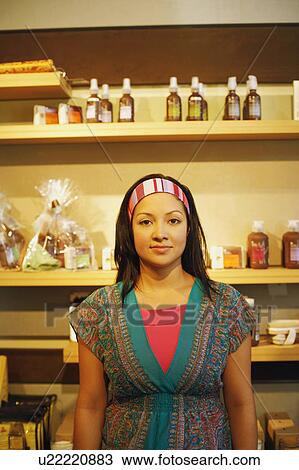 Stock Image - Portrait of a young woman standing in a store. Fotosearch