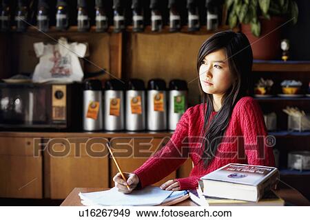 Young woman writing on a sheet of paper and thinking View Large Photo Image Stock Photo - Young woman writing on a sheet of paper and thinking. Fotosearch
