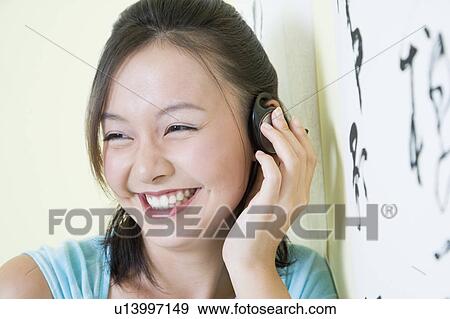 Stock Photo - Close-up of a young woman wearing headphones and listening to music. Fotosearch