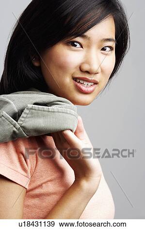 Stock Photo - Portrait of a young woman holding a jacket. Fotosearch