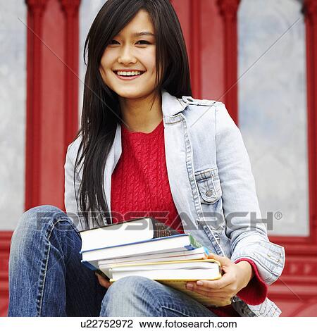 Portrait of a young woman holding books and smiling View Large Photo Image Stock Image - Portrait of a young woman holding books and smiling. Fotosearch