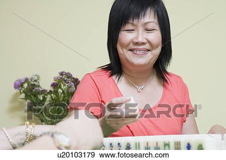 Stock Photo - Close-up of a mature woman playing mahjong and smiling. Fotosearch