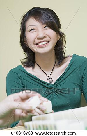 Stock Image - Close-up of a woman's hand playing with blocks and a young woman smiling in the background. Fotosearch
