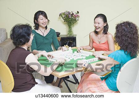Stock Image - Four women playing with blocks at a table and smiling. Fotosearch