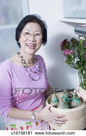 Portrait of a senior woman holding dumplings in a bamboo steamer View Large Photo Image Stock Image - Portrait of a senior woman holding dumplings in a bamboo steamer. Fotosearch