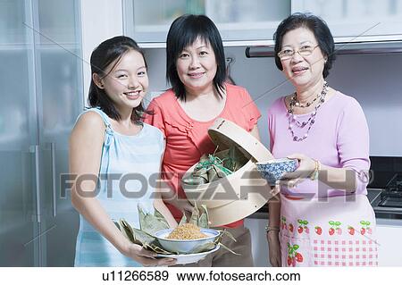 Stock Photo - Portrait of a senior woman with her daughter and granddaughter in a kitchen. Fotosearch