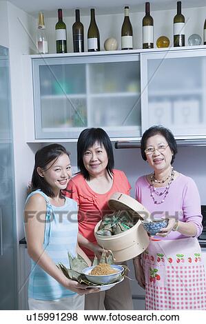 Stock Photo - Portrait of a senior woman with her daughter and granddaughter in a kitchen. Fotosearch