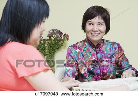 Stock Photo - Senior woman and a mature woman playing mahjong. Fotosearch