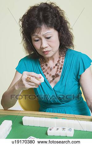 Stock Image - Senior woman playing mahjong. Fotosearch