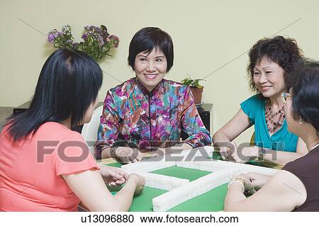 Stock Image - Three senior women and a mature woman playing mahjong. Fotosearch