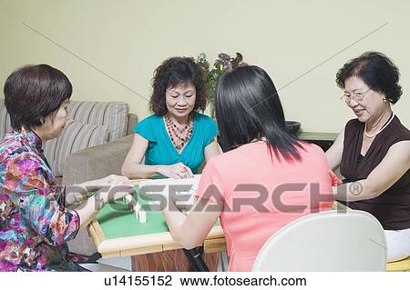 Stock Image - Three senior women and a mature woman playing mahjong. Fotosearch