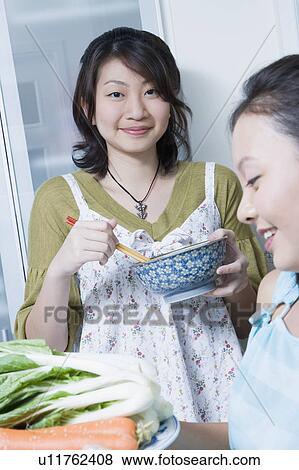 Two young women preparing food in a kitchen View Large Photo Image Stock Photo - Two young women preparing food in a kitchen. Fotosearch