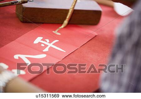 Stock Photo - Close-up of a person's hand painting Chinese script. Fotosearch