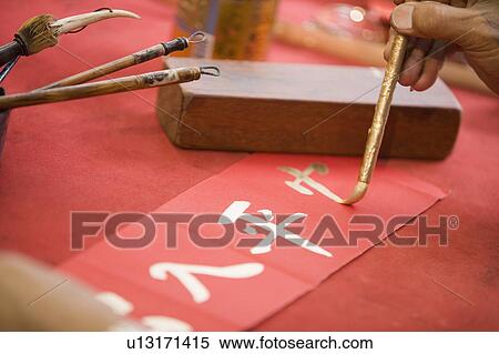 Stock Photography - Close-up of a person's hand painting Chinese script. Fotosearch