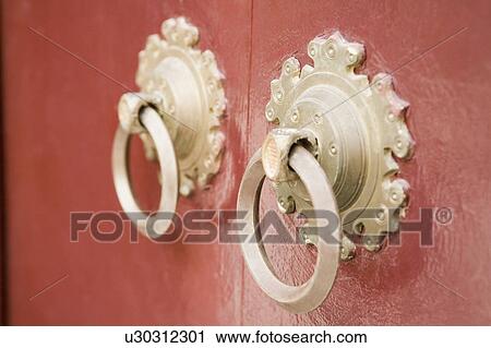 Stock Image - Close-up of two doorknockers on a door. Fotosearch