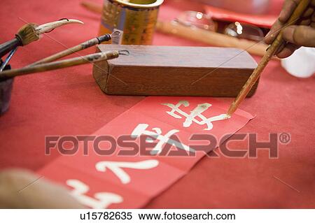 Stock Photography - Close-up of a person's hand painting Chinese script. Fotosearch