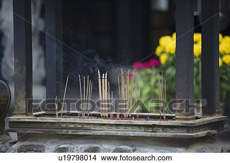 Picture - Close-up of incense sticks burning in a decorative urn in a temple. Fotosearch