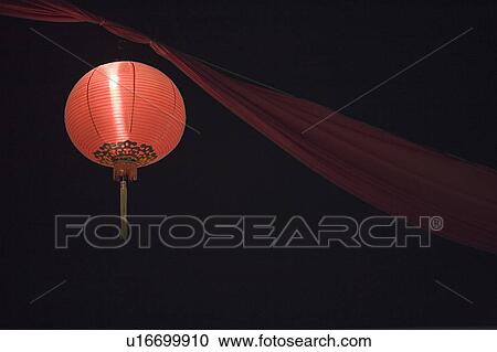 Stock Image - Low angle view of a Chinese lantern lit up at night. Fotosearch