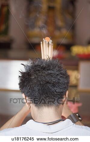 Stock Photography - Rear view of a young man praying in a temple. Fotosearch
