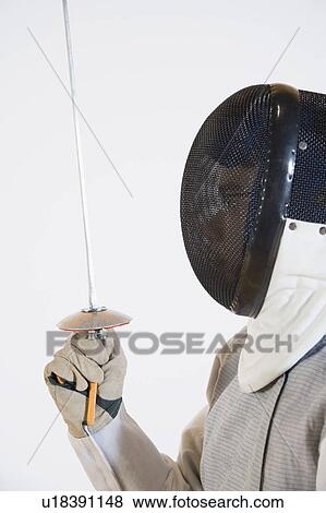 Close-up of a person wearing a fencing mask and holding a fencing foil View Large Photo Image Stock Photo - Close-up of a person wearing a fencing mask and holding a fencing foil. Fotosearch