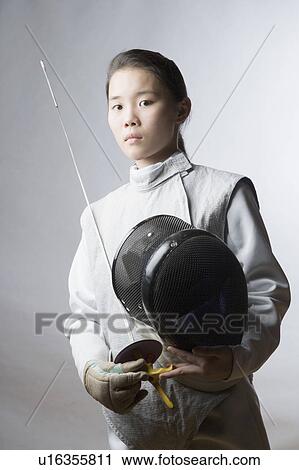 Stock Image - Portrait of a female fencer holding a sword and a fencing mask. Fotosearch