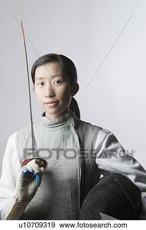 Portrait of a female fencer holding a sword and a fencing mask View Large Photo Image Stock Photo - Portrait of a female fencer holding a sword and a fencing mask. Fotosearch