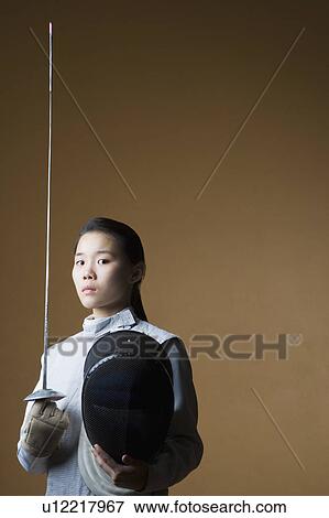 Stock Photo - Portrait of a female fencer holding a sword and a fencing mask. Fotosearch