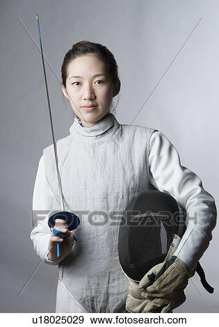 Stock Photo - Portrait of a female fencer holding a sword and a fencing mask. Fotosearch