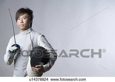 Picture - Portrait of a male fencer holding a sword and a fencing mask. Fotosearch