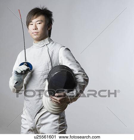 Stock Image - Portrait of a male fencer holding a sword and a fencing mask. Fotosearch