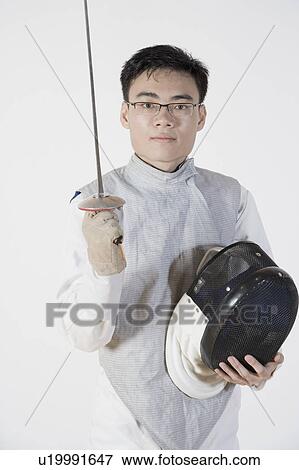 Portrait of a male fencer holding a fencing foil and a fencing mask View Large Photo Image Stock Photo - Portrait of a male fencer holding a fencing foil and a fencing mask. Fotosearch