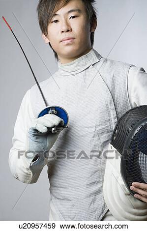 Stock Photo - Portrait of a male fencer holding a sword and a fencing mask. Fotosearch