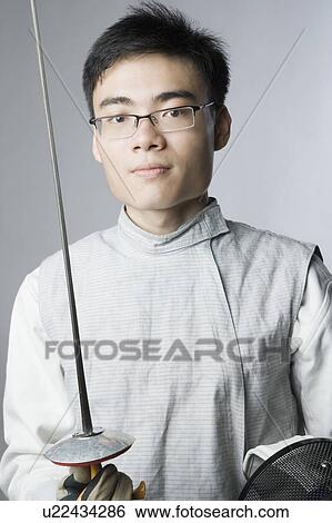 Stock Photograph - Portrait of a male fencer holding a sword and a fencing mask. Fotosearch