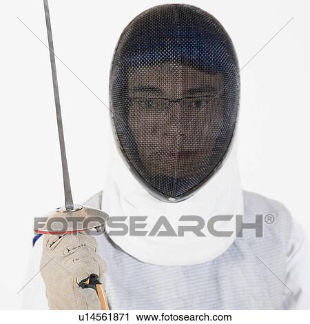 Stock Image - Portrait of a male fencer wearing fencing mask and holding a fencing foil. Fotosearch