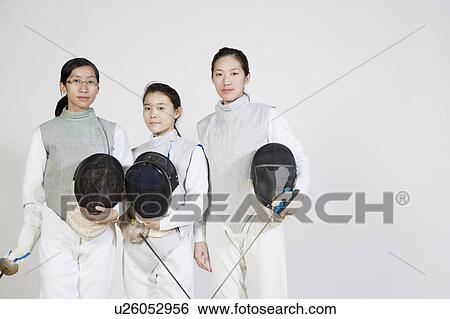 Stock Photograph - Portrait of three female fencers holding fencing foils and fencing masks. Fotosearch
