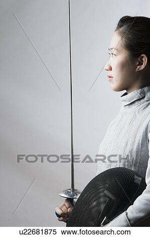 Side profile of a female fencer holding a sword and a fencing mask View Large Photo Image Stock Photography - Side profile of a female fencer holding a sword and a fencing mask. Fotosearch