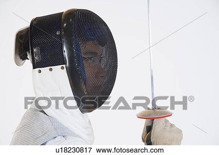 Stock Photo - Side profile of a fencer wearing a fencing mask and holding a fencing foil. Fotosearch
