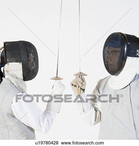 Stock Photo - Close-up of a man and a woman wearing fencing masks and holding fencing foils. Fotosearch