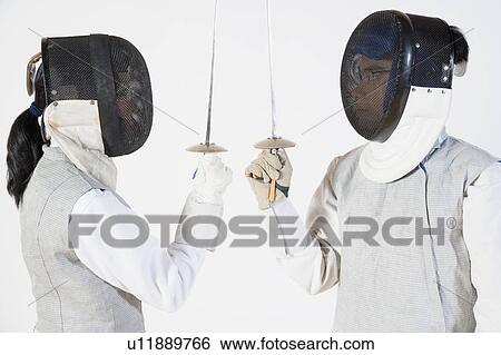 Stock Photograph - Close-up of a man and a woman wearing fencing masks and holding fencing foils. Fotosearch