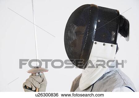 Close-up of a person wearing a fencing mask and holding a fencing foil View Large Photo Image Stock Photograph - Close-up of a person wearing a fencing mask and holding a fencing foil. Fotosearch