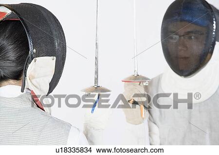 Close-up of two people wearing fencing masks and holding fencing foils View Large Photo Image Picture - Close-up of two people wearing fencing masks and holding fencing foils. Fotosearch