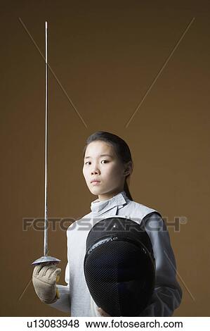 Stock Photo - Portrait of a female fencer holding a sword and a fencing mask. Fotosearch