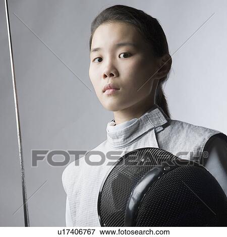 Stock Photo - Portrait of a female fencer holding a sword and a fencing mask. Fotosearch