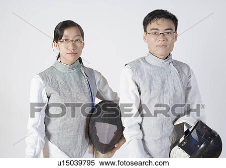 Stock Photography - Portrait of a male and a female fencer holding fencing masks. Fotosearch