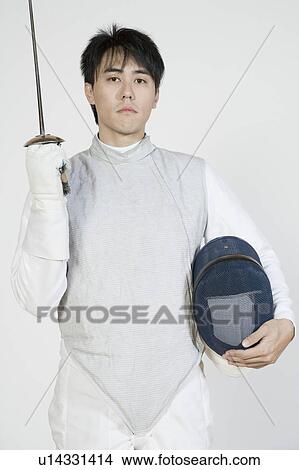 Picture - Portrait of a male fencer holding a fencing foil and a fencing mask. Fotosearch