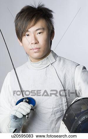 Stock Image - Portrait of a male fencer holding a sword and a fencing mask. Fotosearch